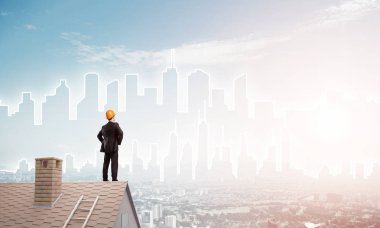 Takım elbiseli genç işadamı ve çatıda kask var. Karışık ortam