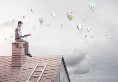 Elinde kırmızı kitap ile evin baca rahat oturan genç adam