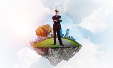 Mavi gök yeşil yüzen ada üzerinde duran zarif emin iş adamı