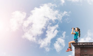 Dürbünle bakan, okul çağındaki sevimli kız çatıyı inşa ediyor.