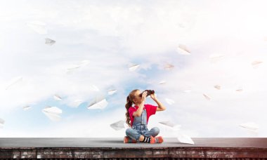 Dürbünle bakan, okul çağındaki sevimli kız çatıyı inşa ediyor.