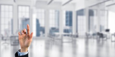 İş kadınının eli ekranda kapalı, arka planda parmak ve ofis var.