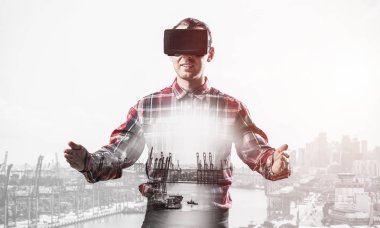 Sanal gerçeklik kulaklığı olan genç bir adam ya da şehrin arka planında 3 boyutlu gözlüklü.