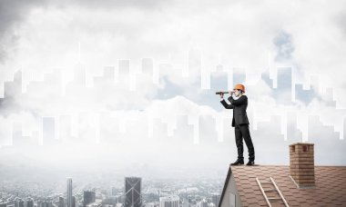 Takım elbiseli genç işadamı ve çatıda kask var. Karışık ortam