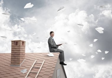 Elinde kırmızı kitap ile ev oturan genç işadamı