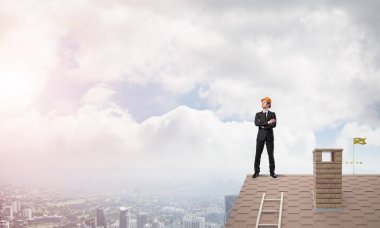 Takım elbiseli genç işadamı ve çatıda kask var. Karışık ortam