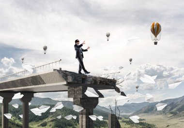 Yürüyüş işadamı kocaman bir boşluk ile beton köprü üzerinde uçan kağıt uçaklar arasında gizli tehditler ve riskler sembolü olarak gözleri. Uçan balonlar ve doğa görünümü arka plan üzerinde. 3D render.