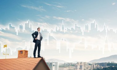 Kararlı genç işadamı evin çatısında dikiliyor ve başka tarafa bakıyor. Karışık ortam