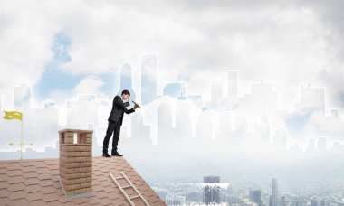 Çatıda takım elbiseli genç bir işadamı var. Karışık ortam