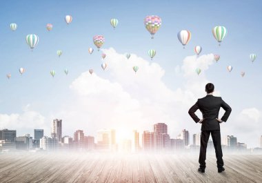 Arka ayakta ve havada uçan aerostats bakarak bir işadamı