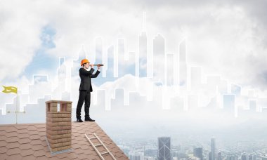 Takım elbiseli genç işadamı ve çatıda kask var. Karışık ortam