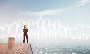 Takım elbiseli genç işadamı ve çatıda kask var. Karışık ortam