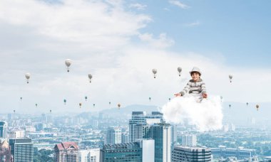 Genç küçük çocuk gözleri koruma kapalı ve seyir sırasında cityscape manzaralı havada bulut üzerinde meditasyon ve aerostats arka plan üzerinde uçan konsantre.