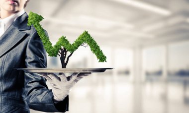 Garson kızın elinde beyaz eldiven yeşil büyüyen grafik arka plan üzerinde office manzaralı metal tepsi üzerinde sunma kırpılmış görüntü.