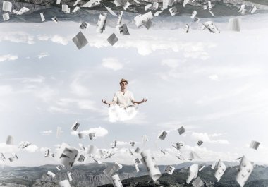 Genç adam gözleri koruma kapalı ve seyir bulut kağıtları uçan arasında ve doğa dünyalar arasında üzerinde meditasyon sırasında konsantre.