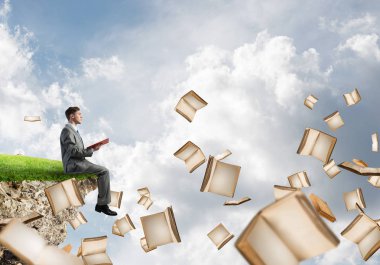 Genç işadamı ellerinde kırmızı kitap ile bir uçurumun kenarında üzerinde yüzen