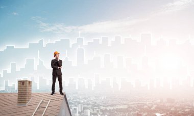 Takım elbiseli genç işadamı ve çatıda kask var. Karışık ortam