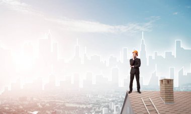 Takım elbiseli genç işadamı ve çatıda kask var. Karışık ortam