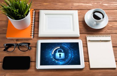 Ofis eşyalarıyla iş yeri ve ekranda asma kilit simgeleri olan tablet