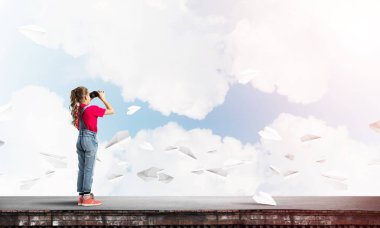 Dürbünle bakan, okul çağındaki sevimli kız çatıyı inşa ediyor.