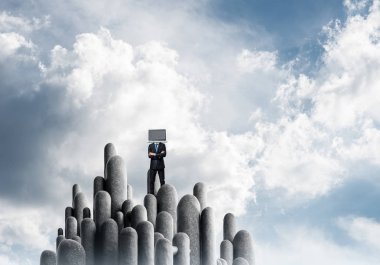 Arka plan üzerinde duran güzel gökyüzü ile taş sütun üst dizüstü bilgisayar kafasına silah tutmak yerine ile takım elbiseli işadamı geçti.