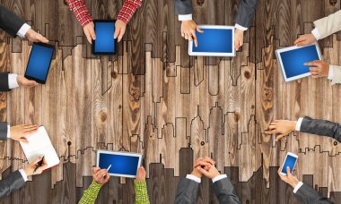 Ellerinde cihazlar bulunan bir grup insan, iletişim ve ağın sembolü olarak birlikte çalışıyor.