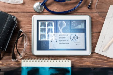 Beyaz tablet bilgisayar ve doktor aletleri ahşap masada.