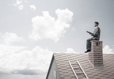 Elinde kırmızı kitap ile ev oturan takım elbiseli genç işadamı