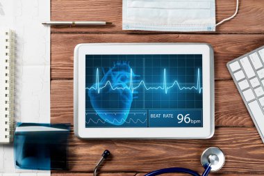 Beyaz tablet bilgisayar ve doktor aletleri ahşap masada.