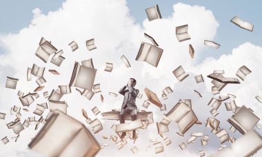 Genç yığın kitap üzerinde oturan ve avuç içi gözlerle kapsayan bir işadamı şok