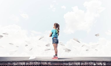 Sevimli kız etrafında uçan çatı ve kağıt uçaklar binasında ayakta