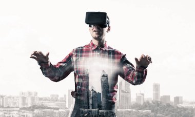 Sanal gerçeklik kulaklığı olan genç bir adam ya da şehrin arka planında 3 boyutlu gözlüklü.