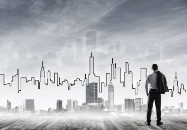 İşadamı arkasını dönüp modern iş merkezinin siluetine bakıyor.