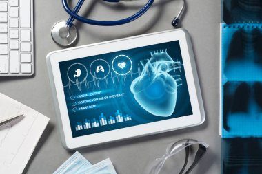 Gri yüzeyde beyaz tablet ve doktor araçları