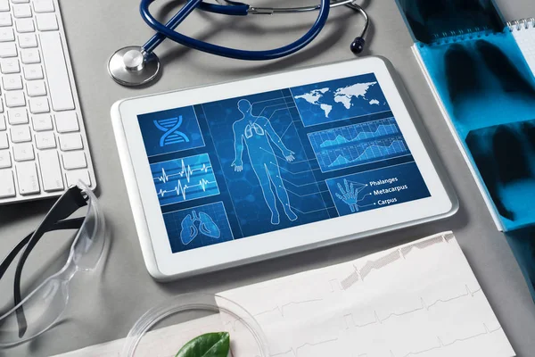 White tablet pc and doctor tools on gray surface