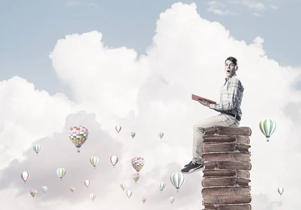 Joven Sorprendido Sentado Montón Libros Con Uno Las Manos — Foto de Stock