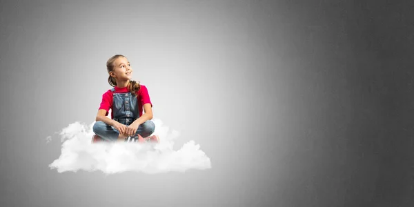 コンクリートの壁の背景に雲に座っているかわいい子供女の子 — ストック写真