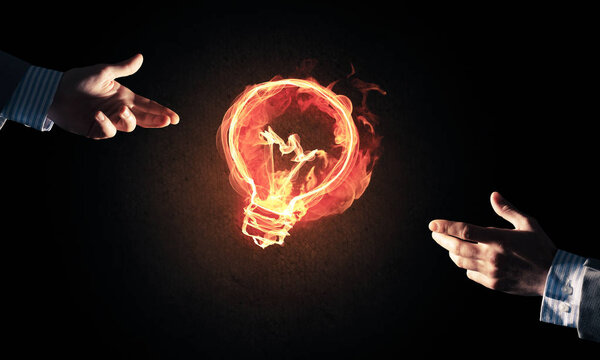 Close of businessman hand showing at glowing fire light bulb icon