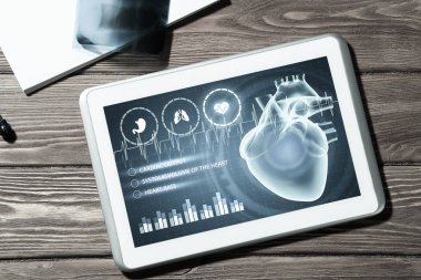 Beyaz tablet bilgisayar ve doktor aletleri ahşap masada.