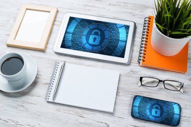 Ofis eşyalarıyla iş yeri ve ekranda asma kilit simgeleri olan tablet