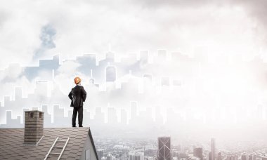 Takım elbiseli genç işadamı ve çatıda kask var. Karışık ortam