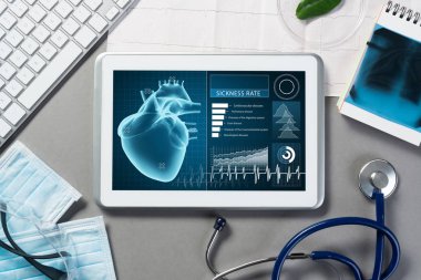 Gri yüzeyde beyaz tablet ve doktor araçları