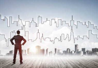 İşadamı arkasını dönüp modern iş merkezinin siluetine bakıyor.