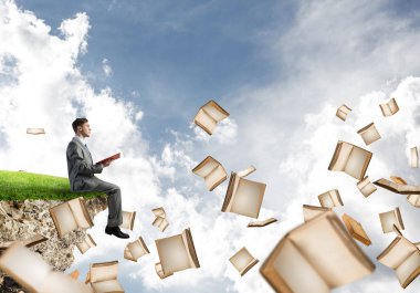 Genç işadamı ellerinde kırmızı kitap ile bir uçurumun kenarında üzerinde yüzen