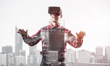 Sanal gerçeklik kulaklığı olan genç bir adam ya da şehrin arka planında 3 boyutlu gözlüklü.