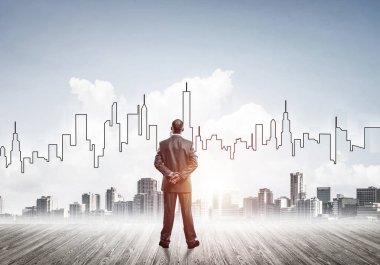 İşadamı arkasını dönüp modern iş merkezinin siluetine bakıyor.