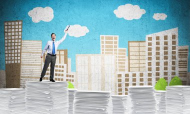 Arka plan üzerinde çizilmiş cityscape ile kağıt evrak yığını üzerinde dururken el kitabı ile uydurarak iş adamı. Karışık teknik.