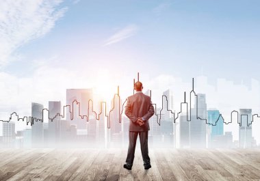 İşadamı arkasını dönüp modern iş merkezinin siluetine bakıyor.