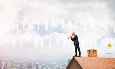 Takım elbiseli genç işadamı ve çatıda kask var. Karışık ortam