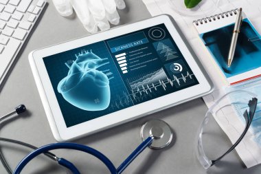 Gri yüzeyde beyaz tablet ve doktor araçları